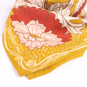 Closeup of a floral patterned bandana, showing a large pink and red flower on the corner. 