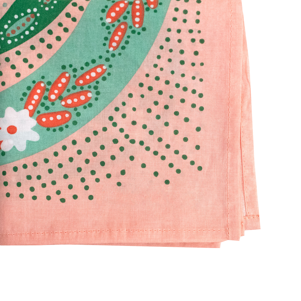 Close-up of a corner of a pink patterned bandana, showing green dots and light green stripes with floral patterns. 