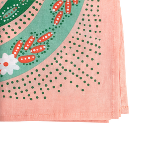 Close-up of a corner of a pink patterned bandana, showing green dots and light green stripes with floral patterns. 