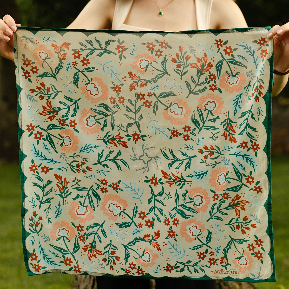 A person holding an unfolded floral patterned bandana.