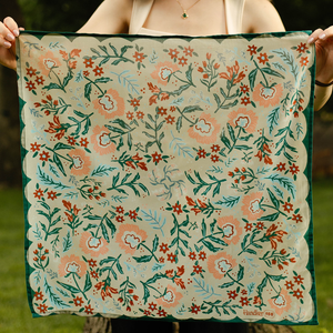 A person holding an unfolded floral patterned bandana.