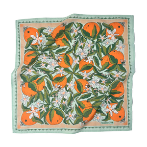 A mint-colored bandana with a pattern of oranges and orange blossoms. 