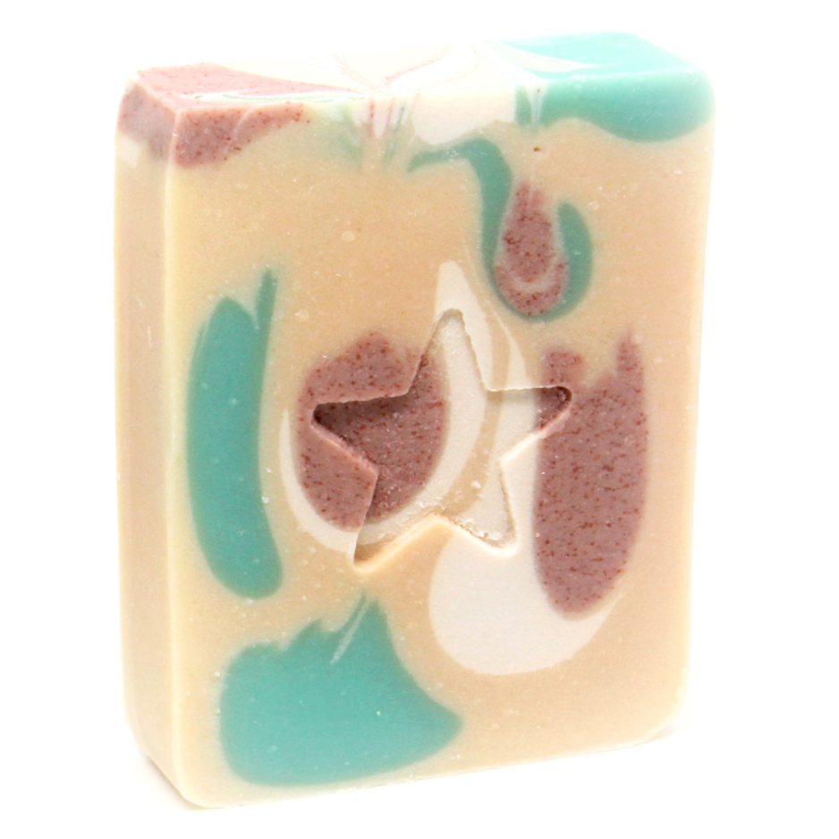 A bar of handmade soap with a white base and accents of green and pink, featuring a star shape cut out.