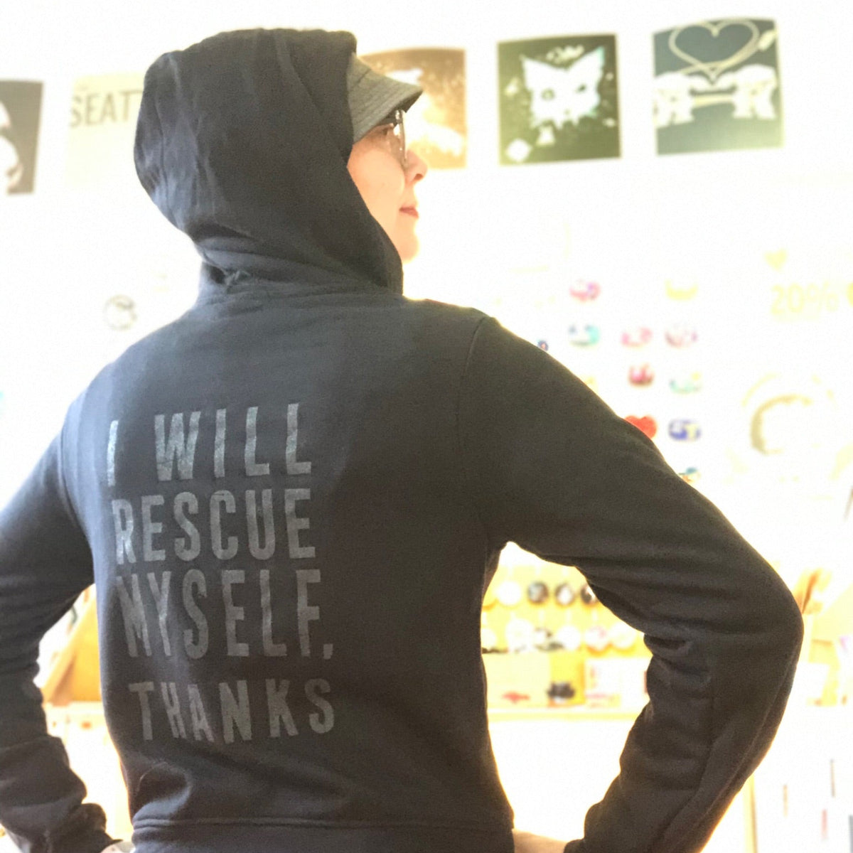 Person wearing a black hoodie with text on the back, standing in a store.