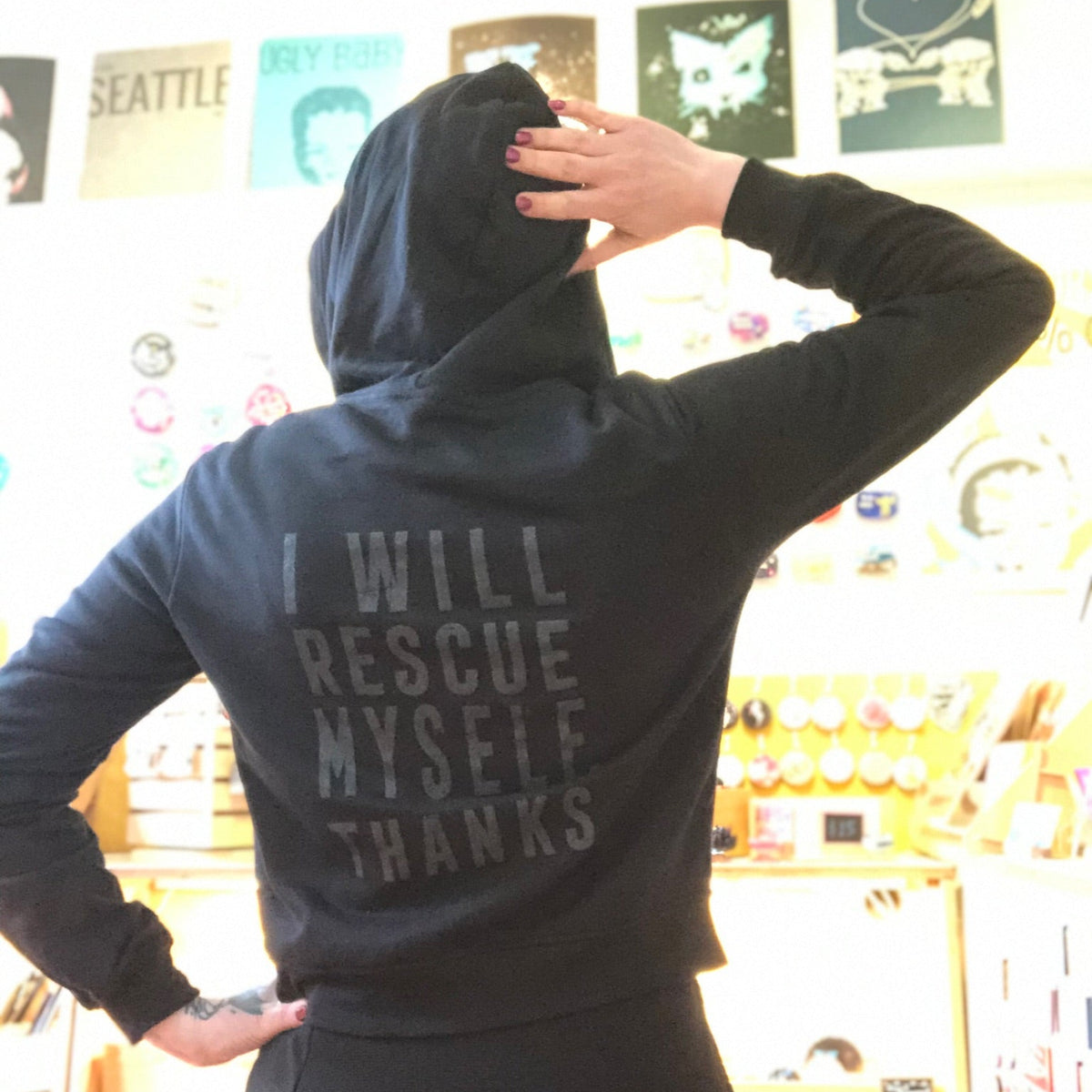 Person wearing a hoodie with text on the back in a store setting