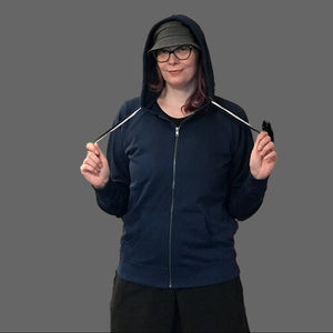 Person holding a product in a store with shelves and clothing racks in the background