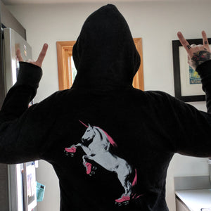 Person wearing a black hoodie with a unicorn graphic in a kitchen