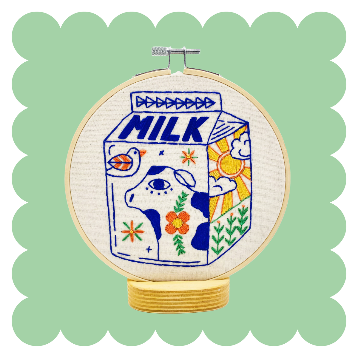 Embroidery hoop with a colorful milk carton design on a light green background
