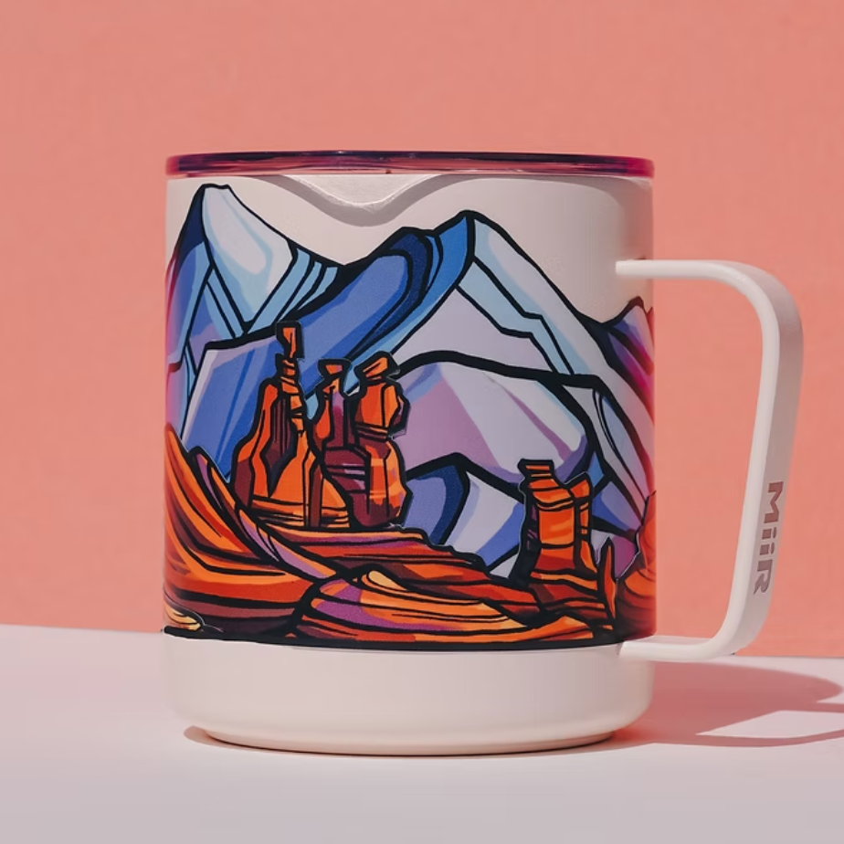 Mug with a colorful mountain and landscape design on a pink background