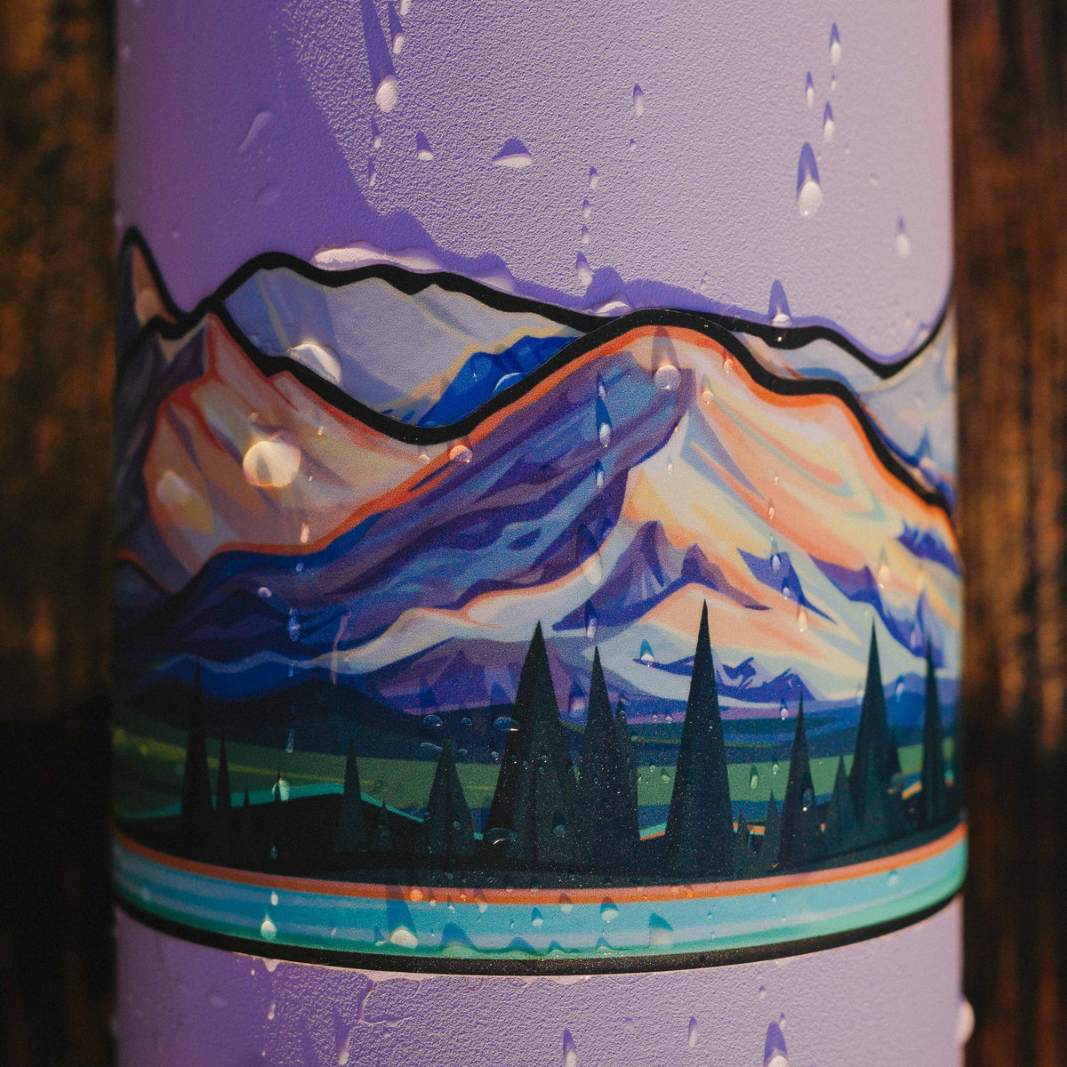 A close up of the cascade volcanoes infinity sticker on a purple water bottle with water drops.