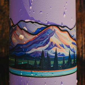 A close up of the cascade volcanoes infinity sticker on a purple water bottle with water drops.