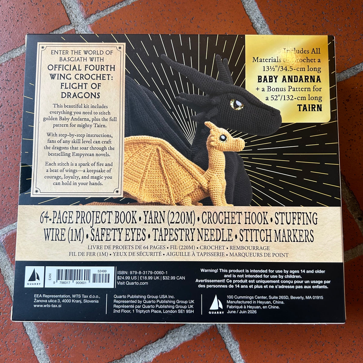 Back cover of a craft project kit titled  laid flat on a red textured surface. The cover features a black background with two crochet dragons and a cream title panel with product details and publisher information.