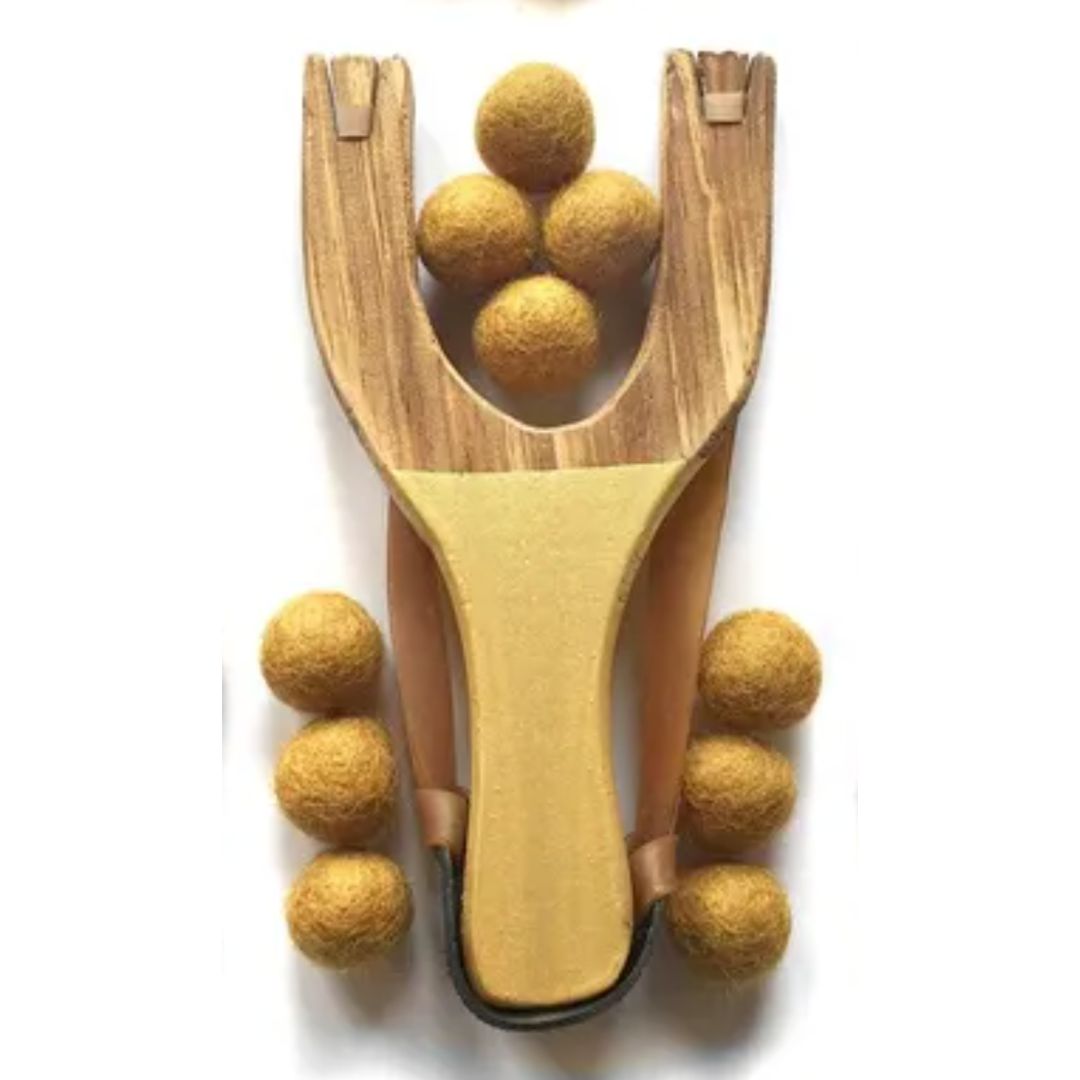 Wooden slingshot with yellow balls on a white background