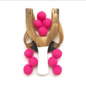 Wooden slingshot with neon pink balls on a white background