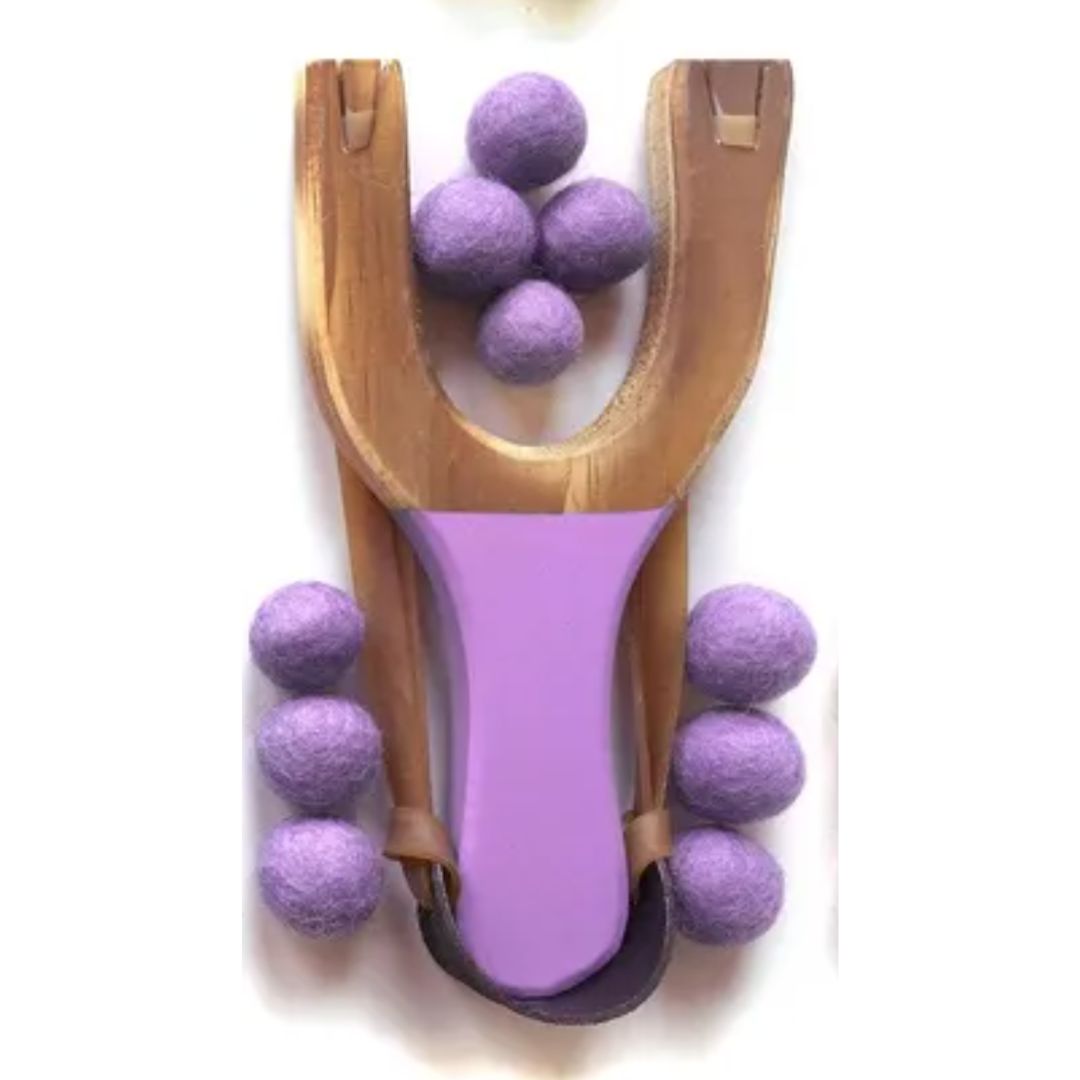 A purple slingshot with purple felt balls against a white background