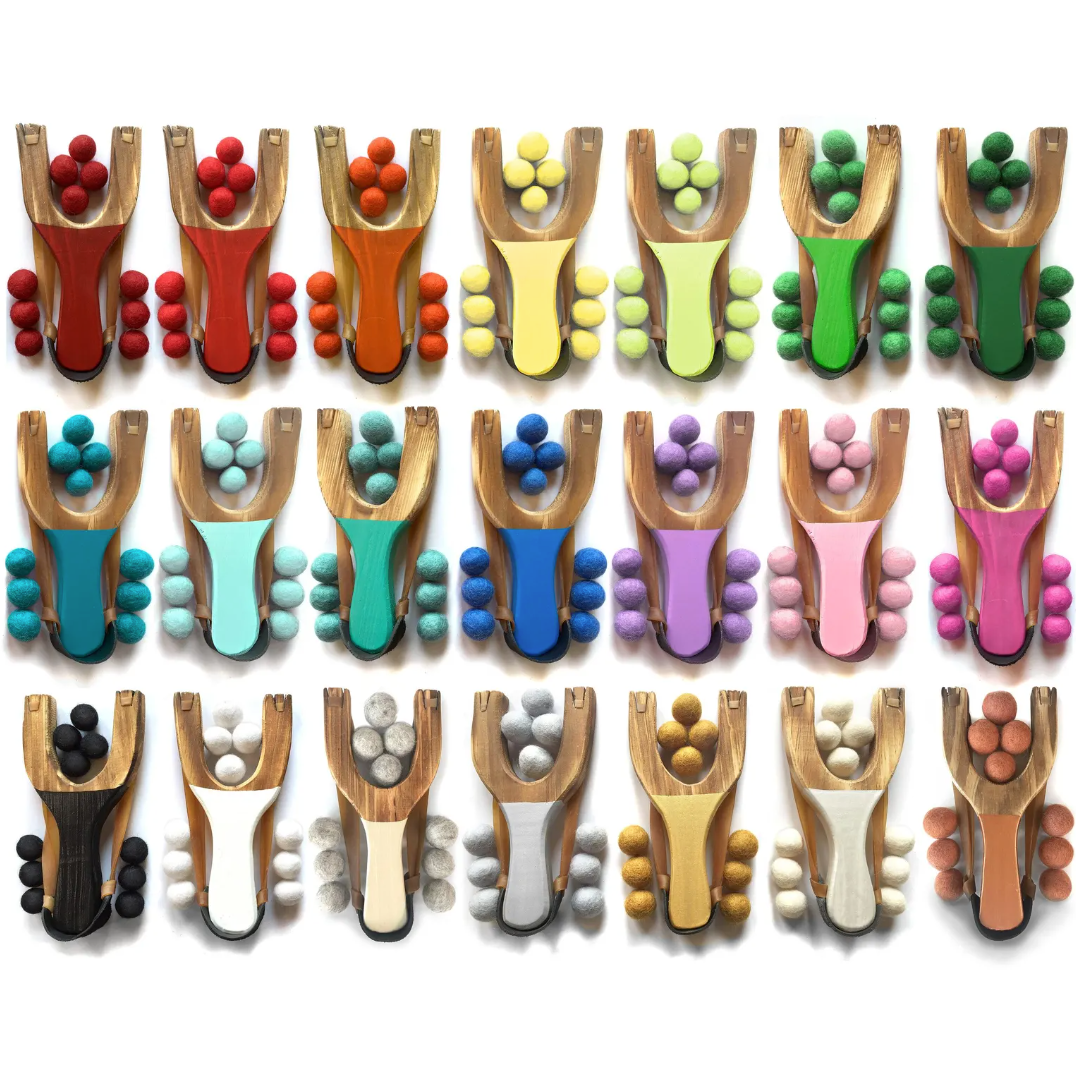 Set of colorful slingshots with felt balls on a white background