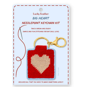 Craft kit of a needlepoint keychain featuring a design of a pink heart on a red background 