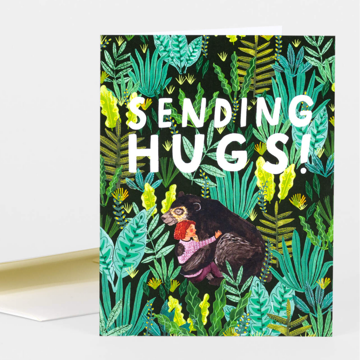 Greeting card with a girl and bear hugging and 'Sending Hugs!' text amidst green foliage