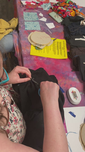 A student removing a corporate logo from an item using reverse applique. 
