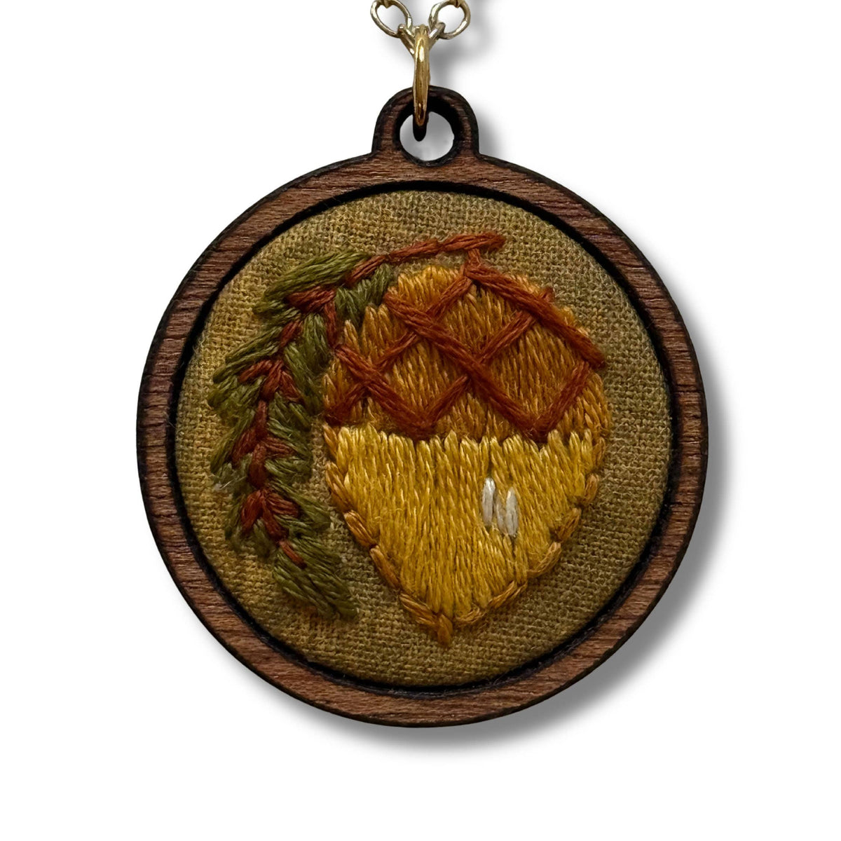 Embroidered pendant with an acorn design on a white background