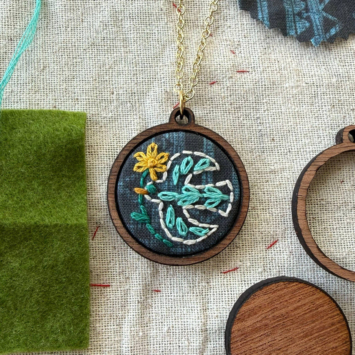 Embroidered necklace with bird design on a textured fabric background