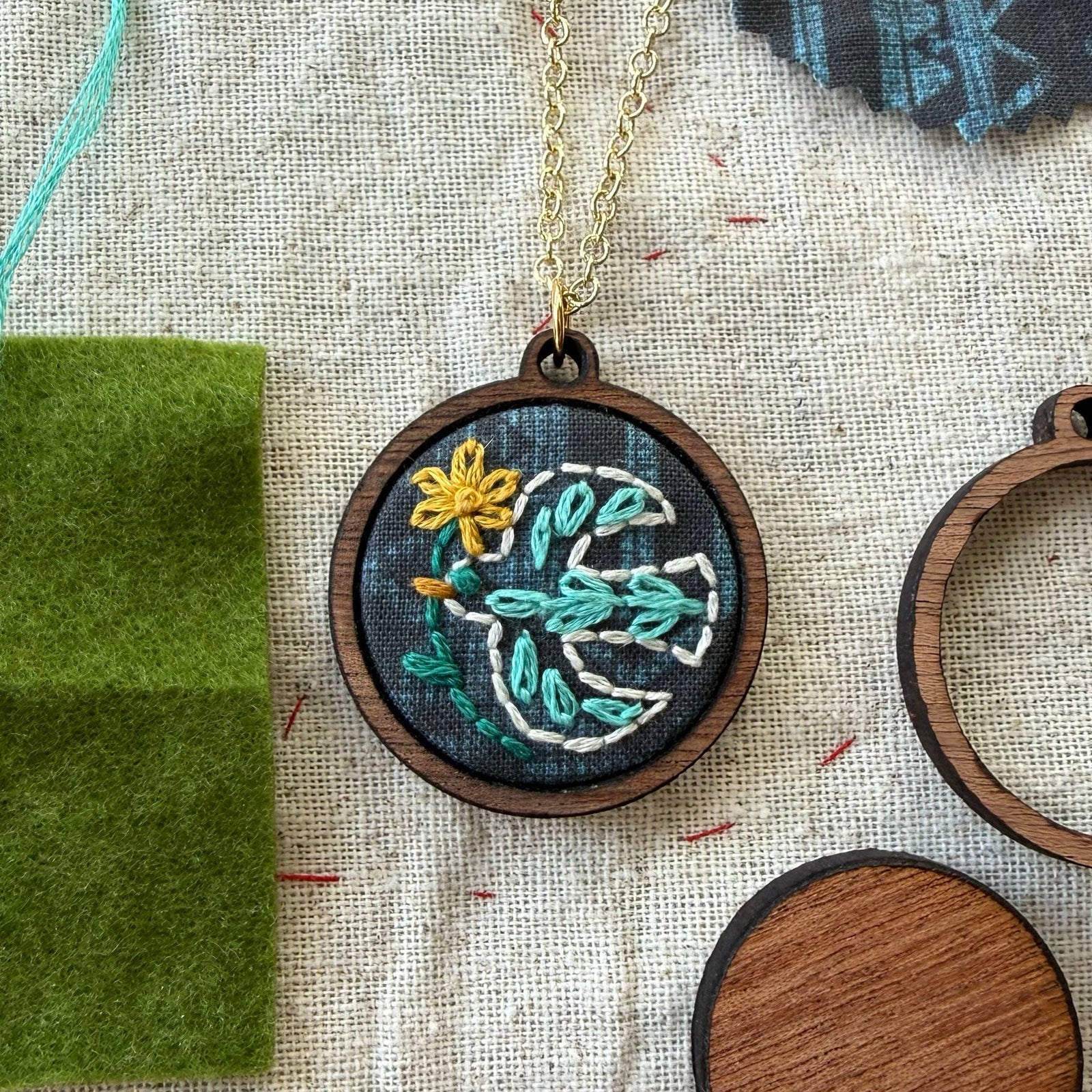 Embroidered necklace with bird design on a textured fabric background