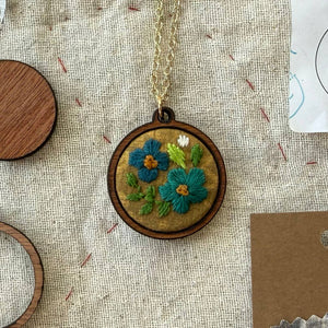 Necklace with floral embroidery pendant on a textured fabric background