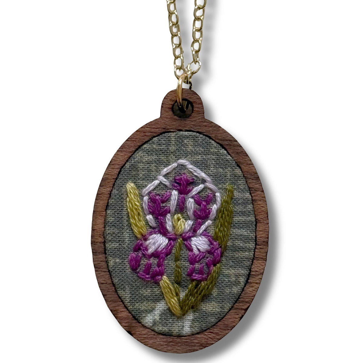Embroidered pendant with floral design on a wooden frame, attached to a gold chain against a white background.
