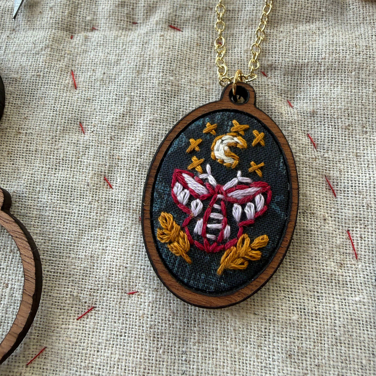 Embroidered pendant necklace on a textured fabric background