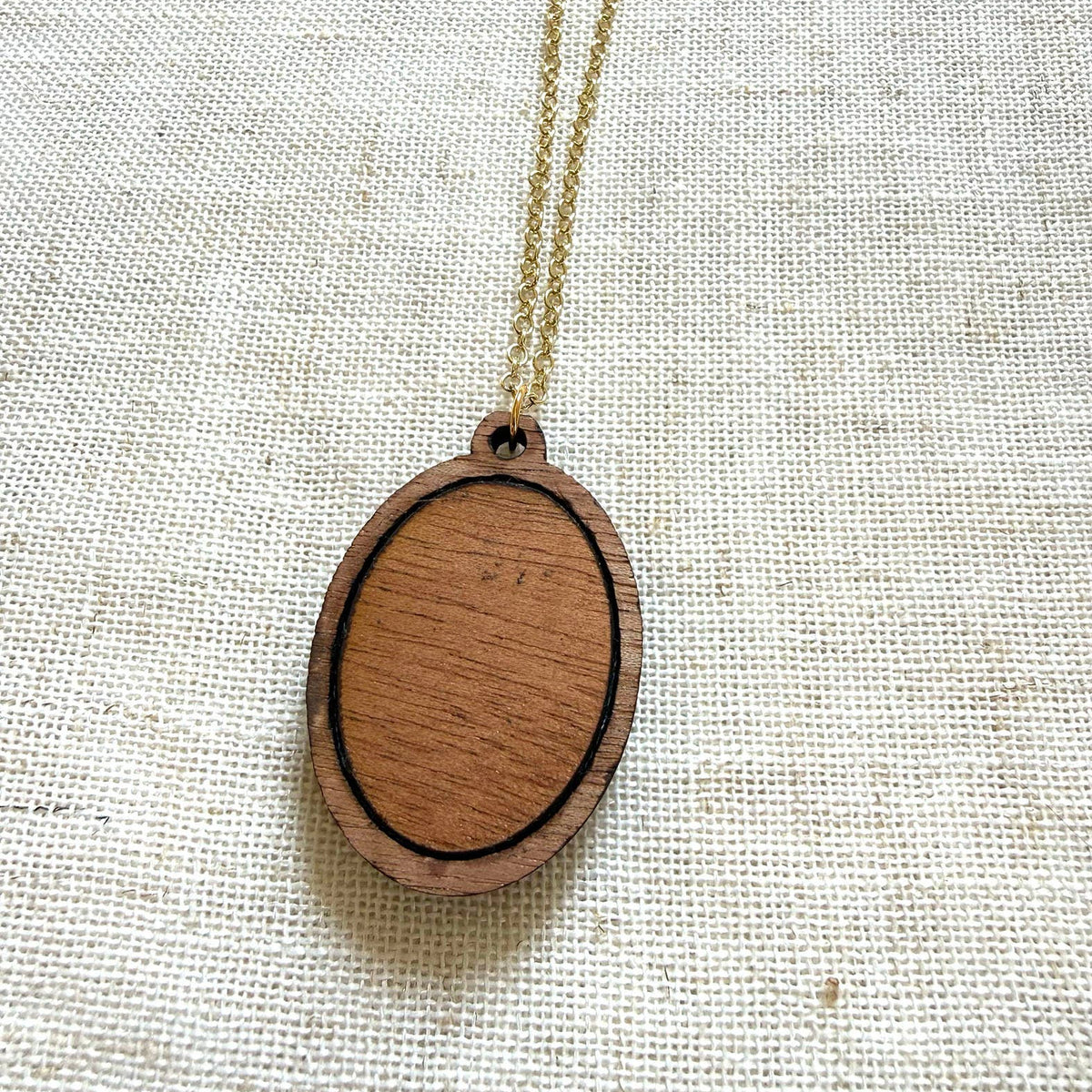 Wooden pendant necklace on a textured fabric background