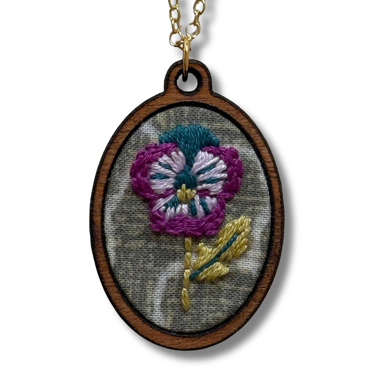 Embroidered flower pendant on a chain against a white background