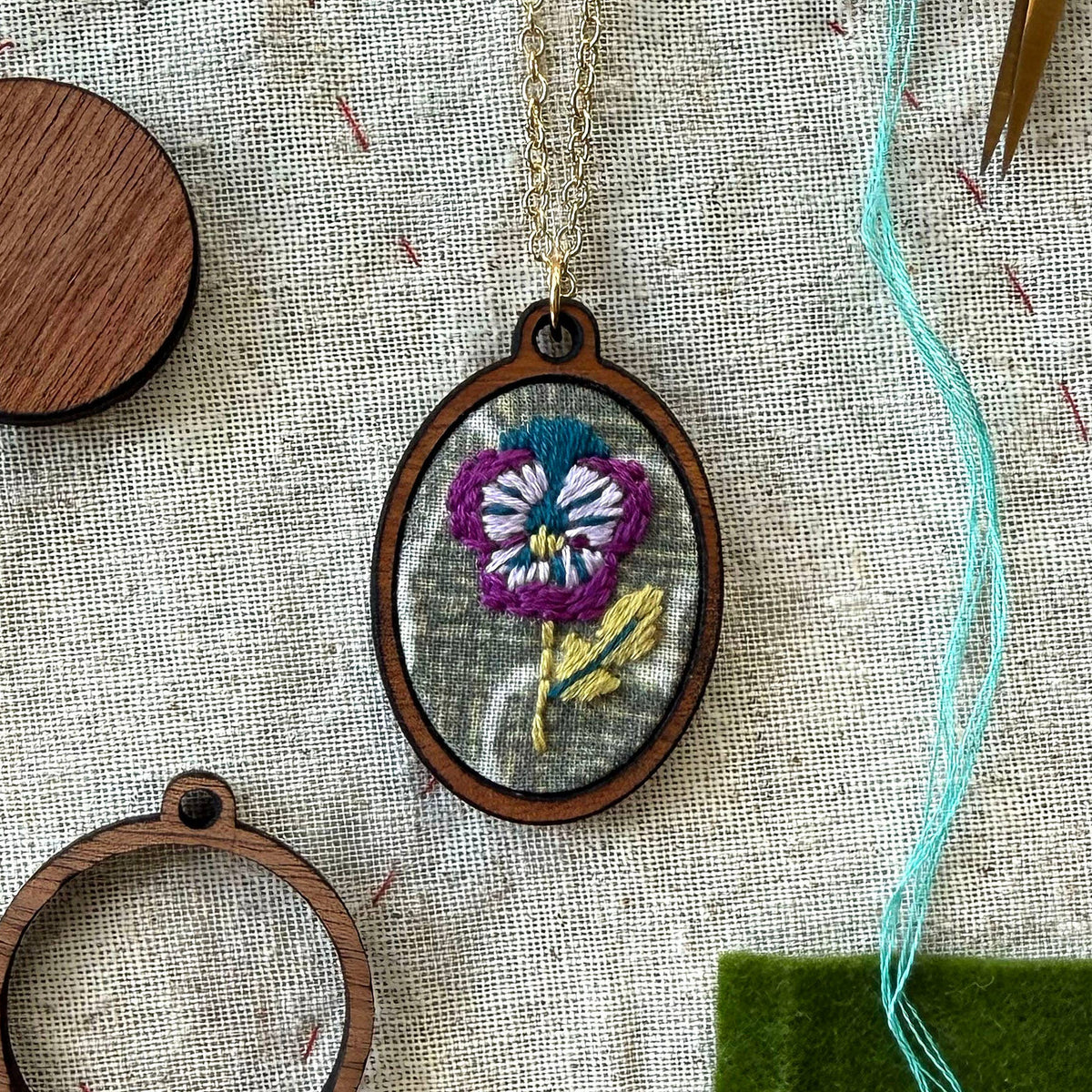 Embroidered pendant with a floral design on a textured fabric background