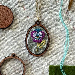 Embroidered pendant with a floral design on a textured fabric background