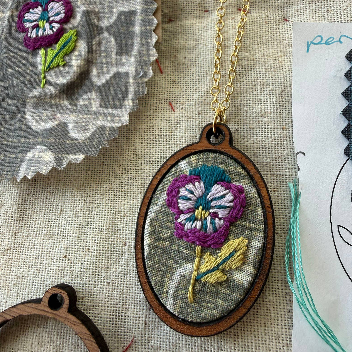 Embroidered necklace with floral design on a textured fabric background