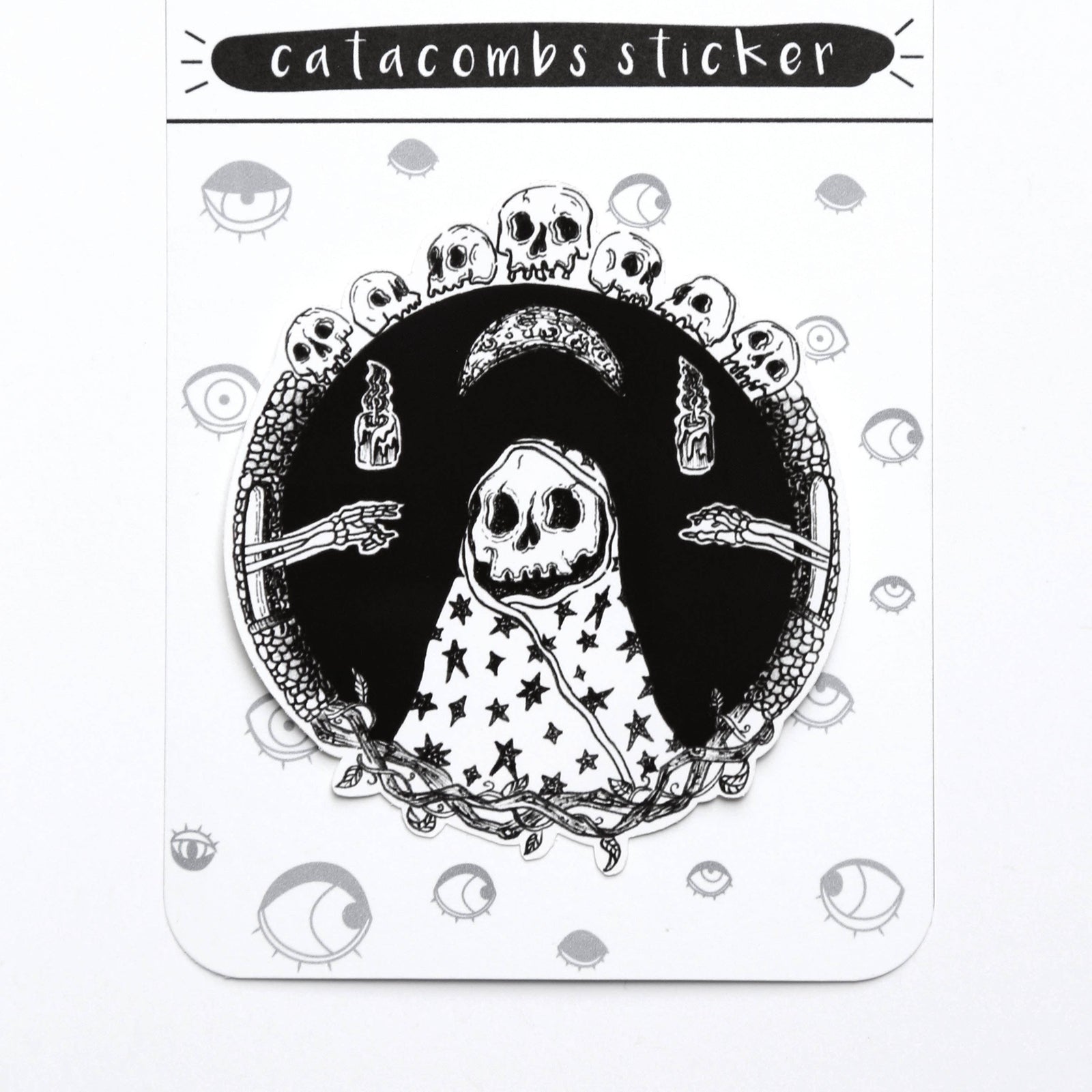 A gothic-themed sticker on its original backing card. The sticker features a black and white illustration of a hooded skeleton figure with stars on its cloak, surrounded by skulls, a crescent moon, and skeletal hands.