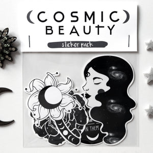 A sticker pack labeled 'COSMIC BEAUTY sticker pack' shown on a white background with decorative celestial props including a black crescent moon, a rhinestone flower brooch, and silver star embellishments. The sticker set includes black-and-white illustrated stickers featuring a woman's profile, a flower, and moon motifs.