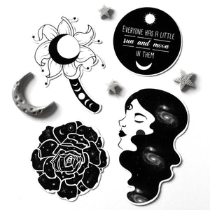 A set of black and white celestial-themed stickers on a white background, featuring a flower with a crescent moon, a moon phase wand, a circular quote sticker, a crescent moon, a rose, and a profile of a woman with galaxy hair.