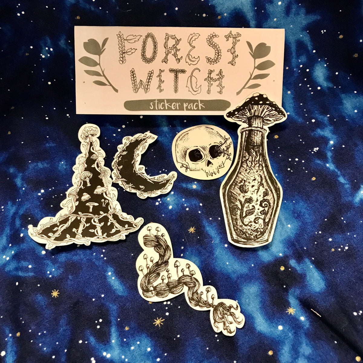 A grouping of five black and white illustrated stickers, including a witch hat, a braid, a crescent moon, a skull, and a potion bottle with a mushroom cork, all against a galaxy background. 