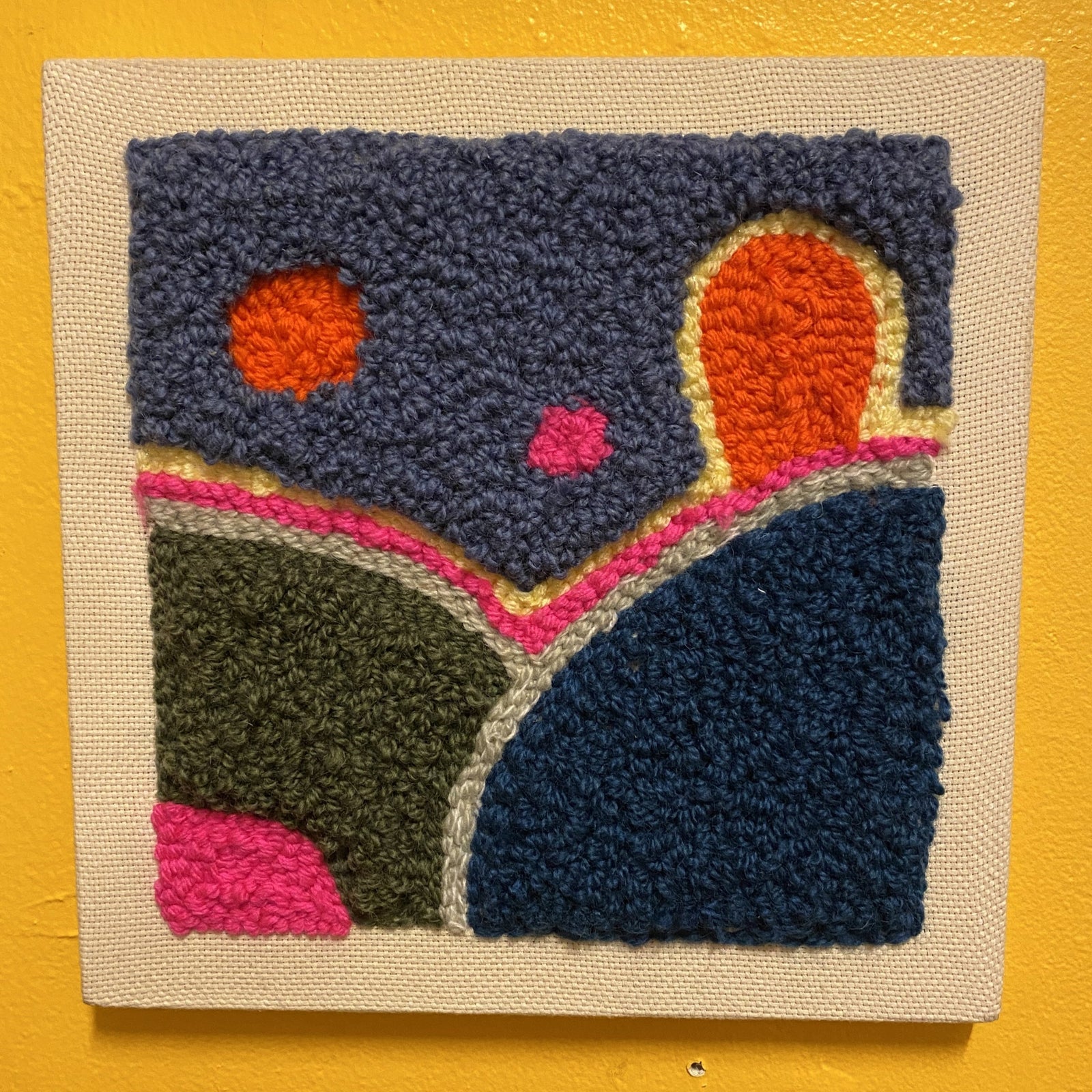 An example of a punch needle wall hanging piece with different stitches and shapes that are different pile heights.