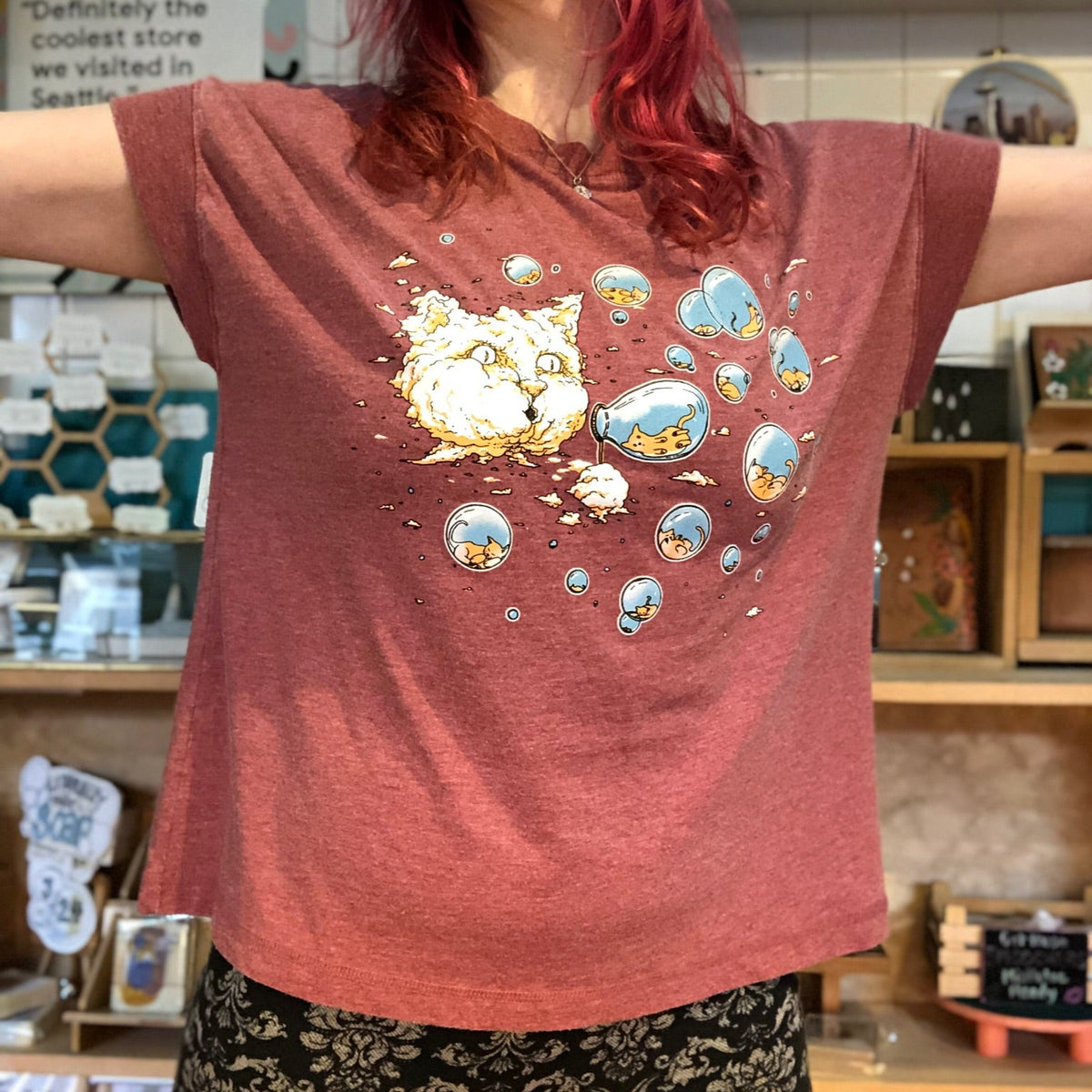 Person wearing a red t-shirt with a cartoon design in a store setting