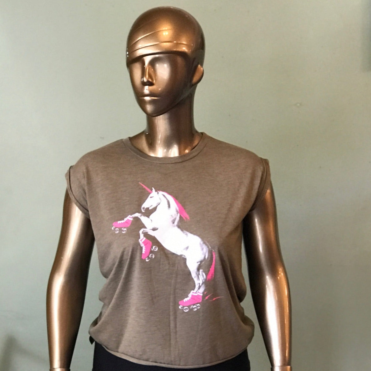 Gold plus-size mannequin wearing a heather olive rolled cuff muscle tee shirt with a hot pink and white roller skating unicorn graphic. 