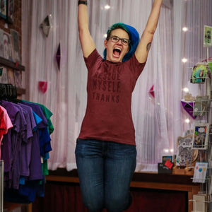 Person wearing a t-shirt with text that says "I will rescue myself, thanks", in a store setting. The person is jumping in the air.