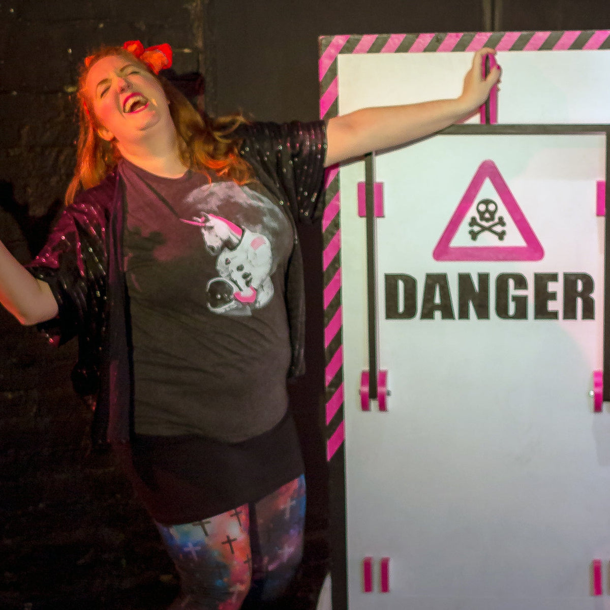 Person posing next to a 'DANGER' sign with a skull and crossbones symbol.