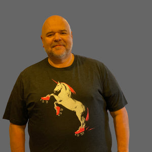 Man wearing a black t-shirt with a graphic design of a unicorn on roller skates, standing in a store.