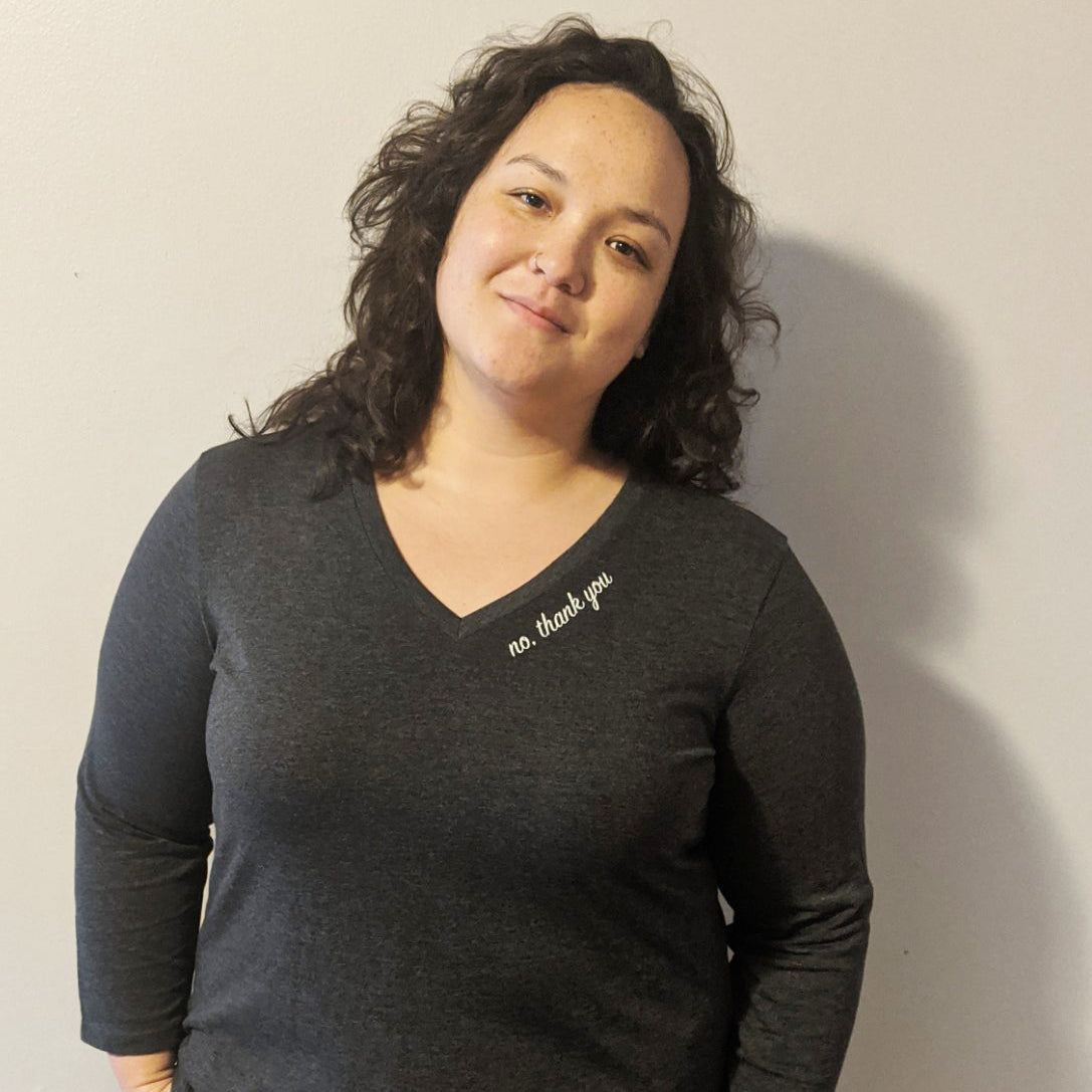 Woman wearing a dark gray shirt with text that says "No, thank you" against a plain background.