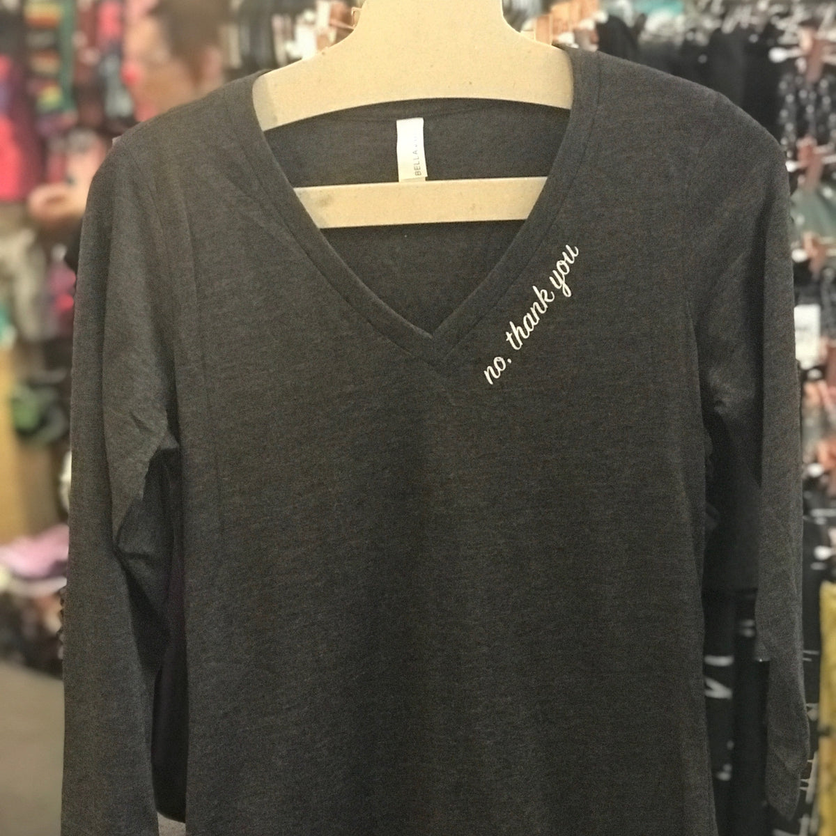 Black long-sleeve shirt with 'no. thank you' text on a mannequin in a store setting.