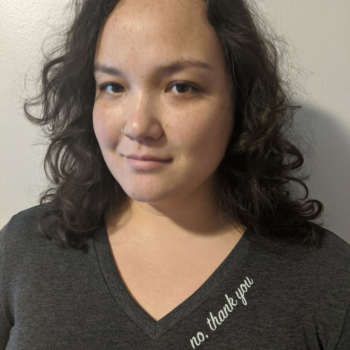 Person wearing a dark gray shirt with 'no, thank you' text against a plain background