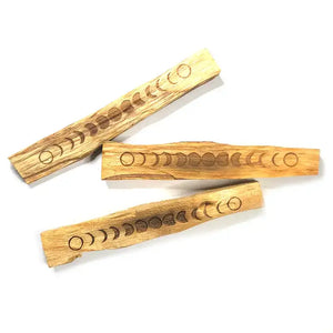 Three wooden sticks with engraved moon phase patterns on a white background