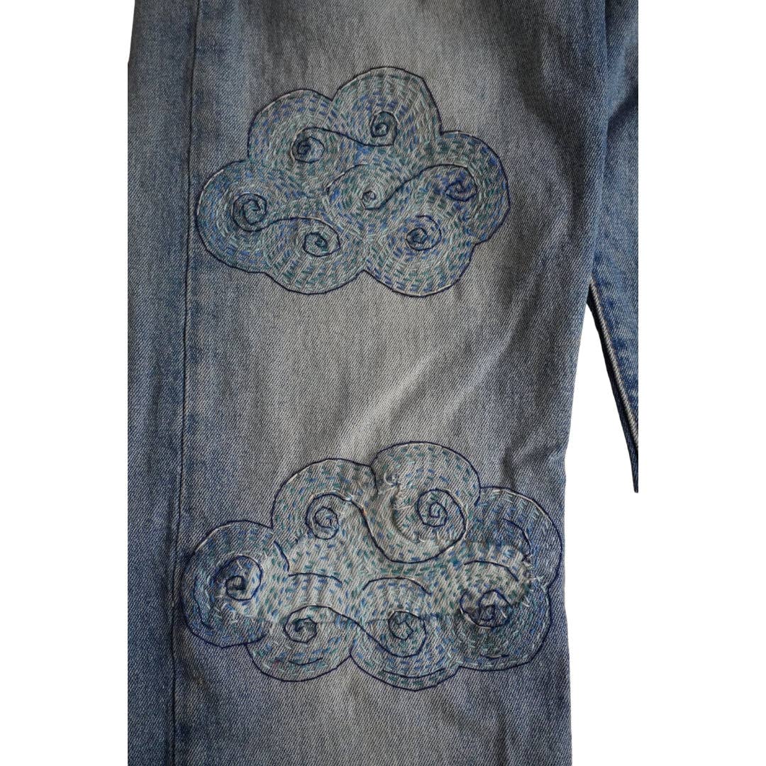 Stitched up example of cloud-shaped visible mending patterns on a pair of jeans. 