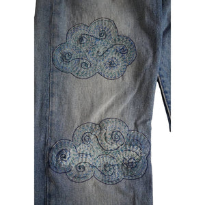 Stitched up example of cloud-shaped visible mending patterns on a pair of jeans. 